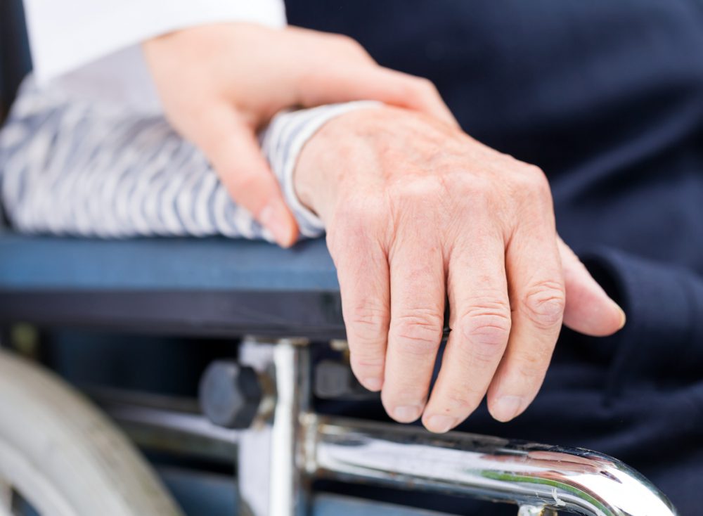 Hands of an elderly woman resting on the wheelchair