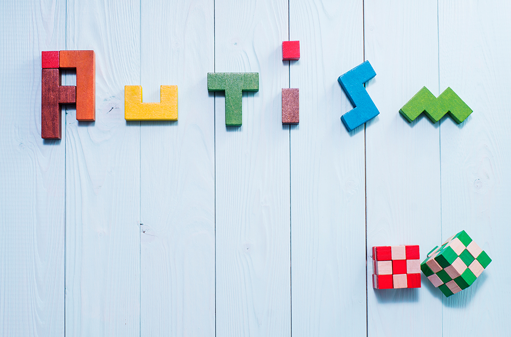The word 'autism' spelt in colourful blocks on a blue background.
