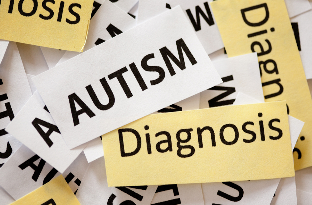 A graphic of yellow and white rectangles that look like snippets of paper, that say autism and diagnosis
