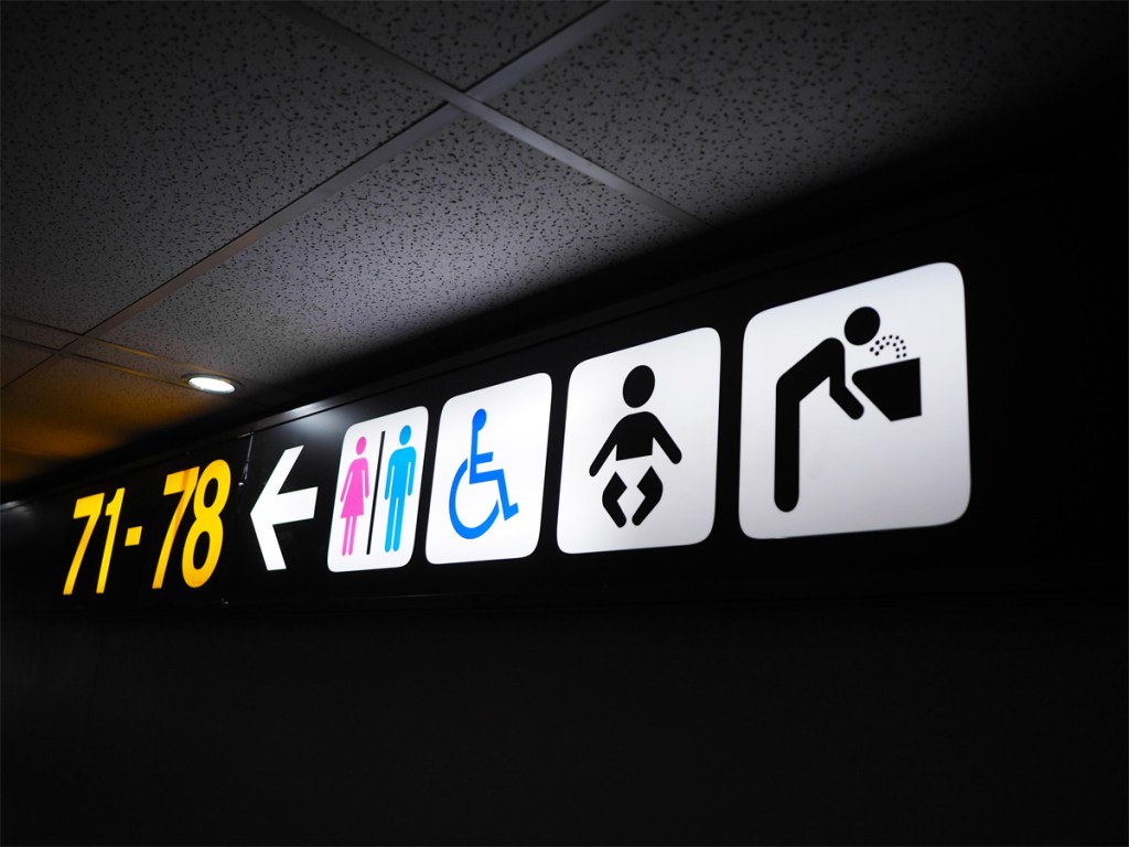 Toilet sign and departures information post at the airport.