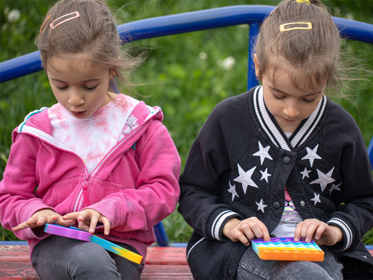 Two blonde children play with colourful toys.