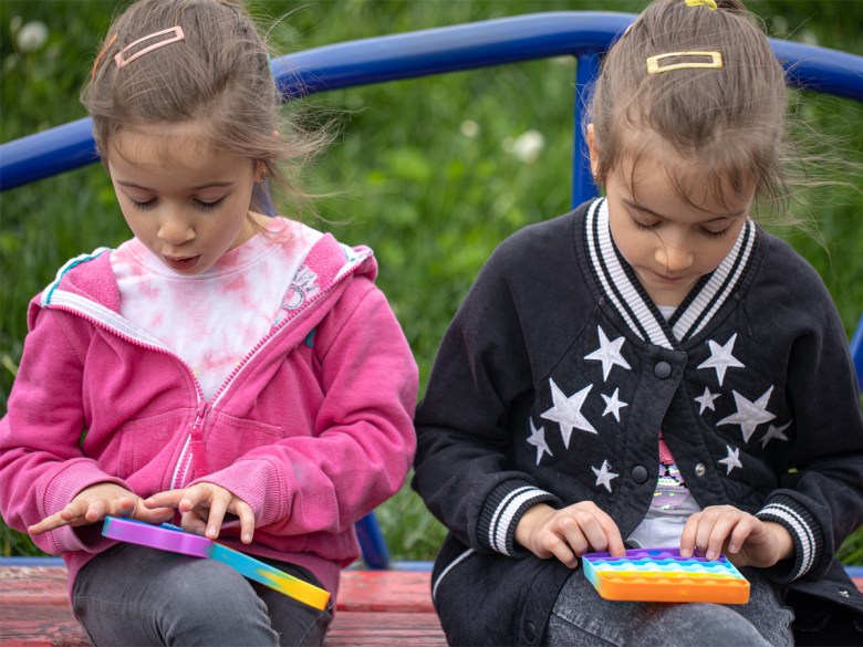 Two blonde children play with colourful toys.