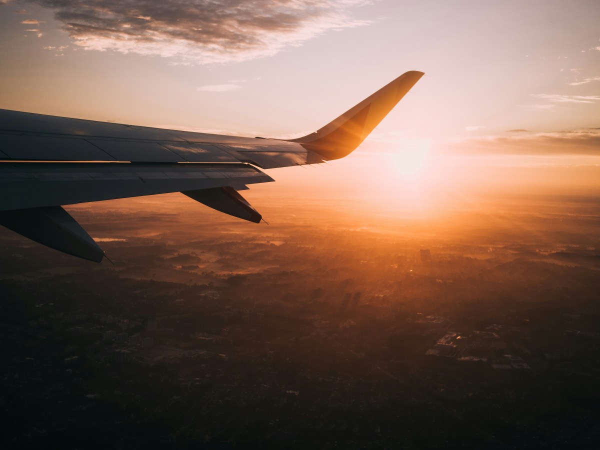 An airplane wing in the sky at sunset.