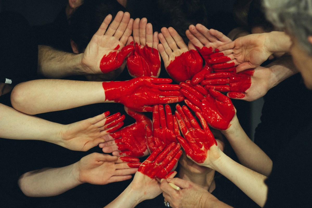 A group of people's hands with red paint on them to represent Foundational Supports.