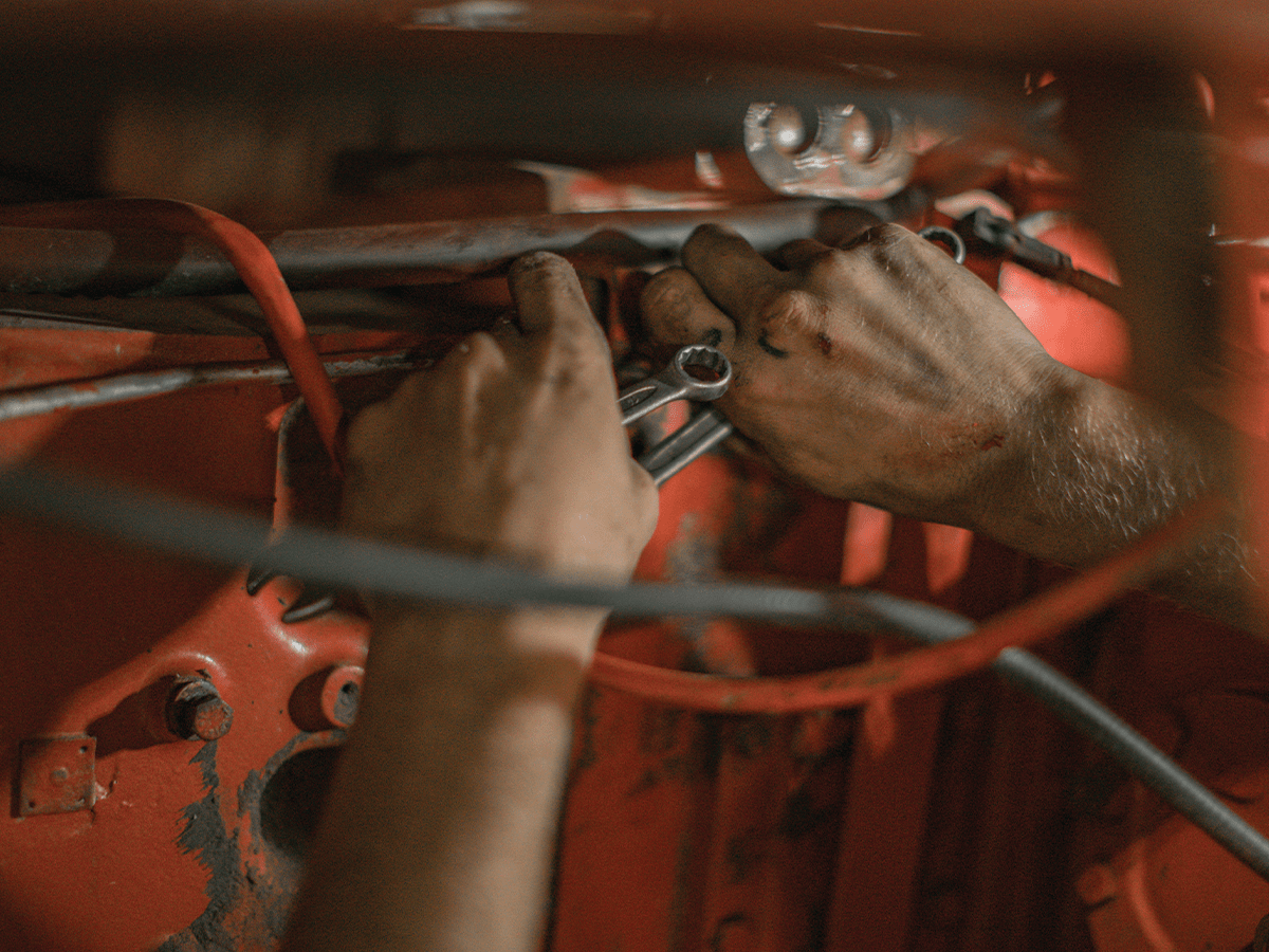 A man's hands working inside a car.