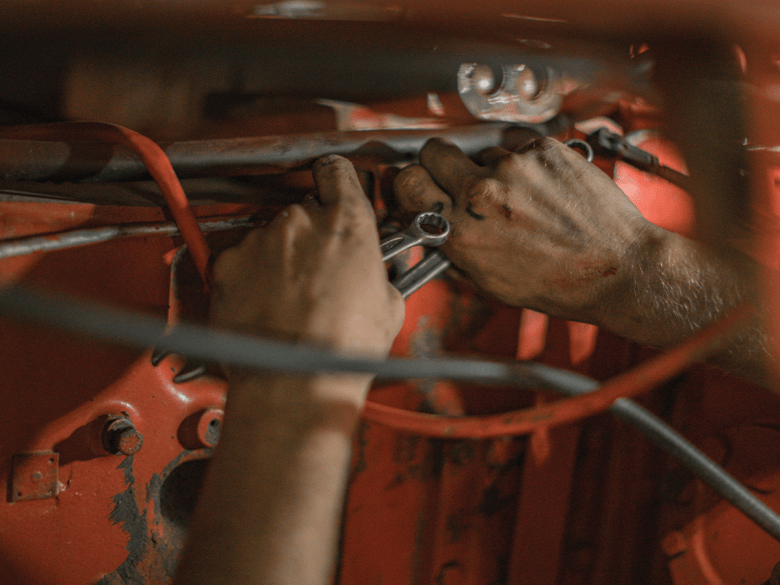 A man's hands working inside a car.