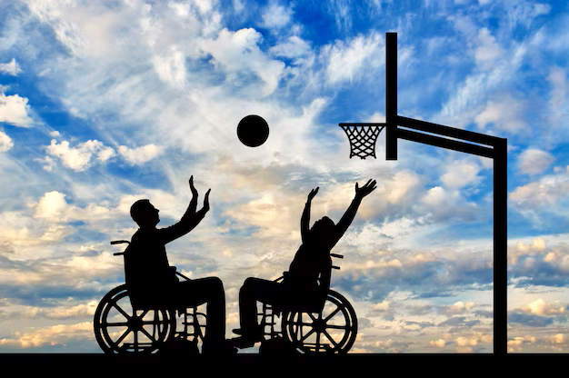 Two people in wheelchairs play basketball. They are silhouetted in black against a blue cloudy sky.
