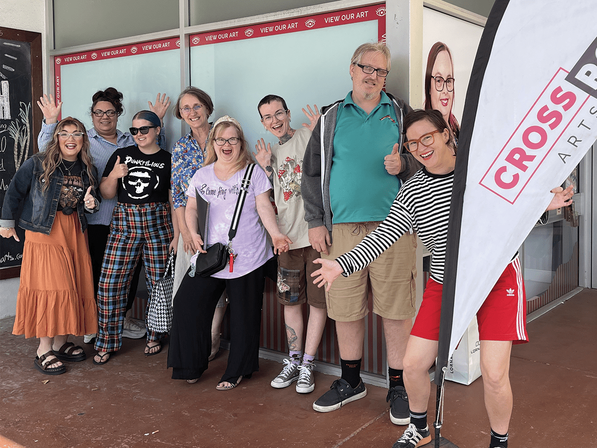 A group of people looking joyful, standing outside a building with a flag that says Crossroad.