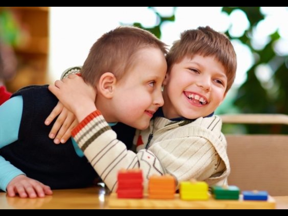 Two young boys playing colourful blocks, hugging and smiling