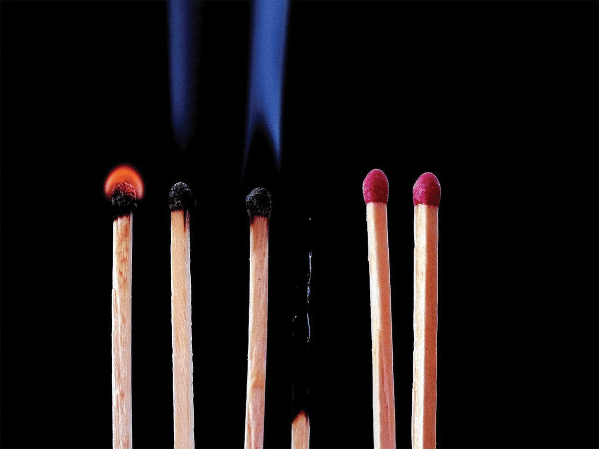 A row of matches, some on fire and one burnt out to a stub.