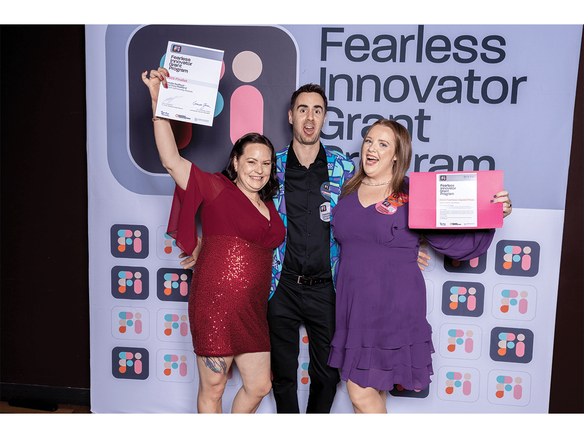 Three people dressed in cocktail style party clothes in bright colours, celebrating at an awards ceremony.