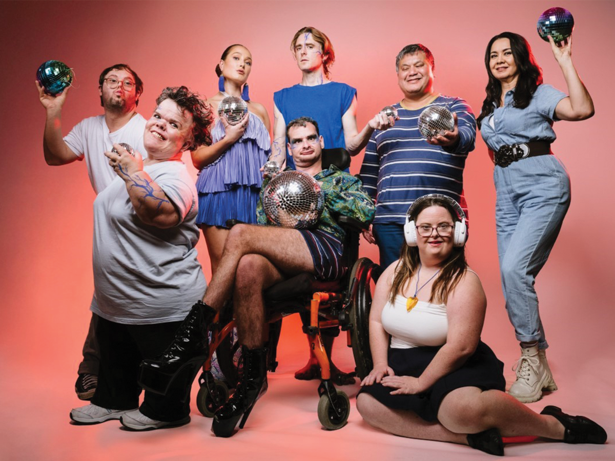 A group of artists with disability posing in a publicity photo for Undercover Festival 2025 against a red background. They look excited and happy.
