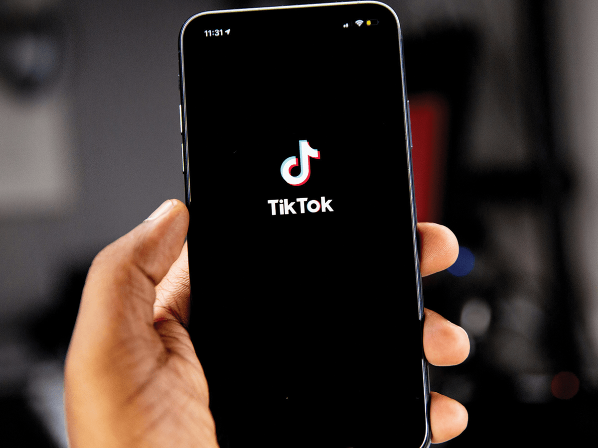 A person's hand holding up a phone with the TikTok logo on the screen.